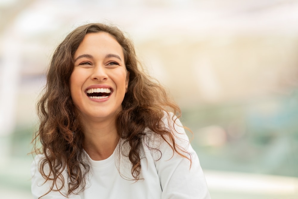 Woman with curly hair with a nice smile because of Endodontic Root Canal