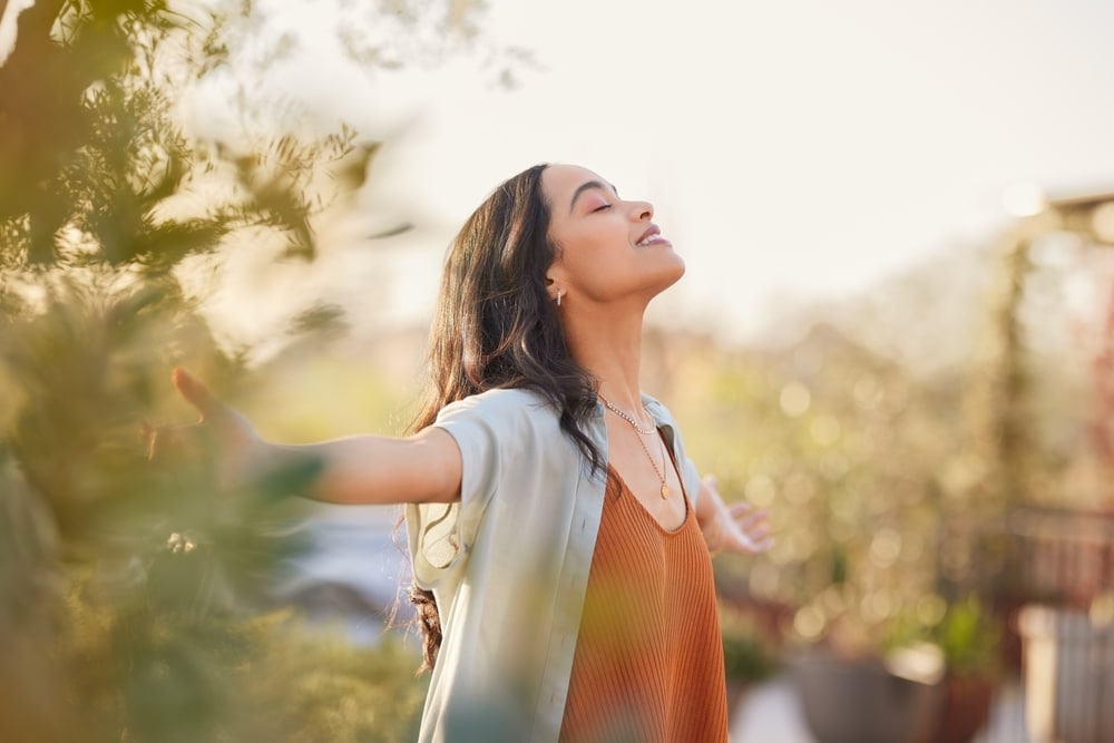 Young woman smiling with arms outstretched enjoying sunshine at Dental Services at Westlake Village Dental