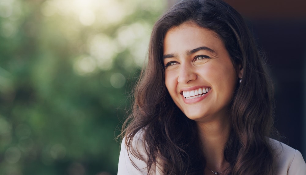 Smiling woman with black hair posing happily outdoors at Dental Services at Westlake Village Dental