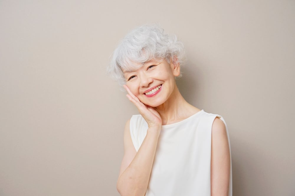 Smiling elderly woman with white hair posing happily indoors at Dental Services at Westlake Village Dental