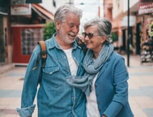 Happy senior couple walking arm in arm outdoors smiling at Dental Services at Westlake Village Dental