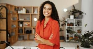 Woman with curly black hair smiling with cross-arms after availing Dental Services at Westlake Village Dental